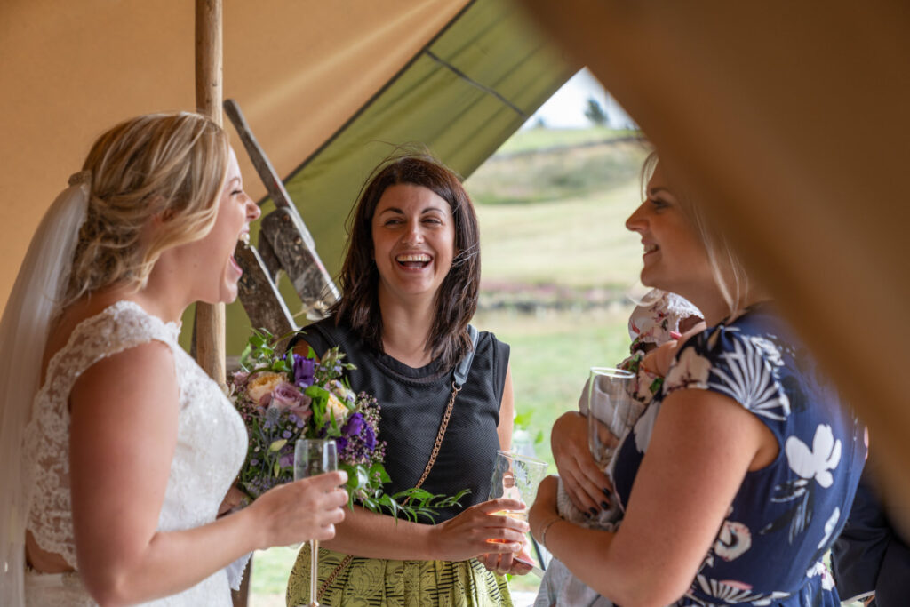 Bride and guests laughing together at Wedbarn