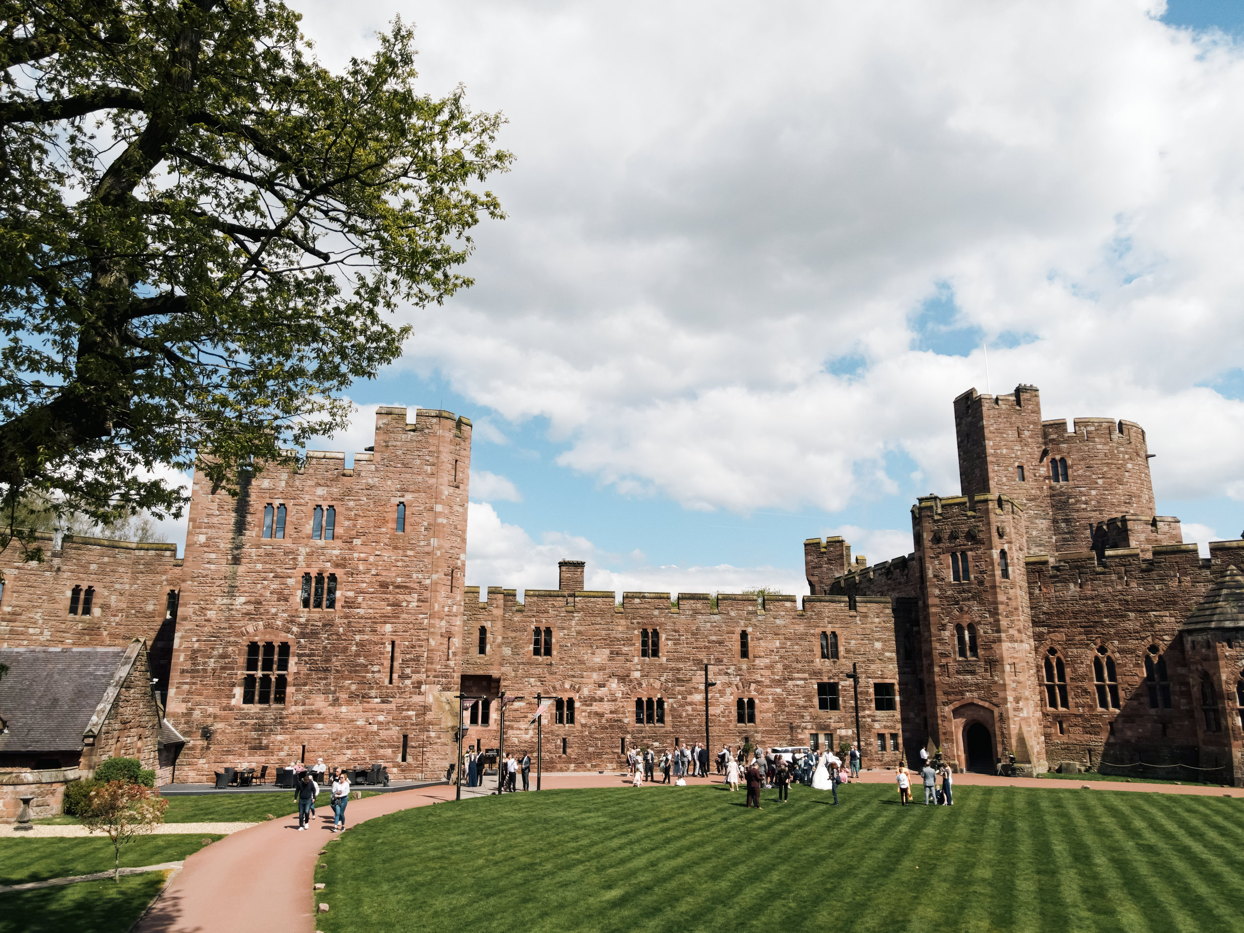 View of Peckforton Castle with wedding guests outside