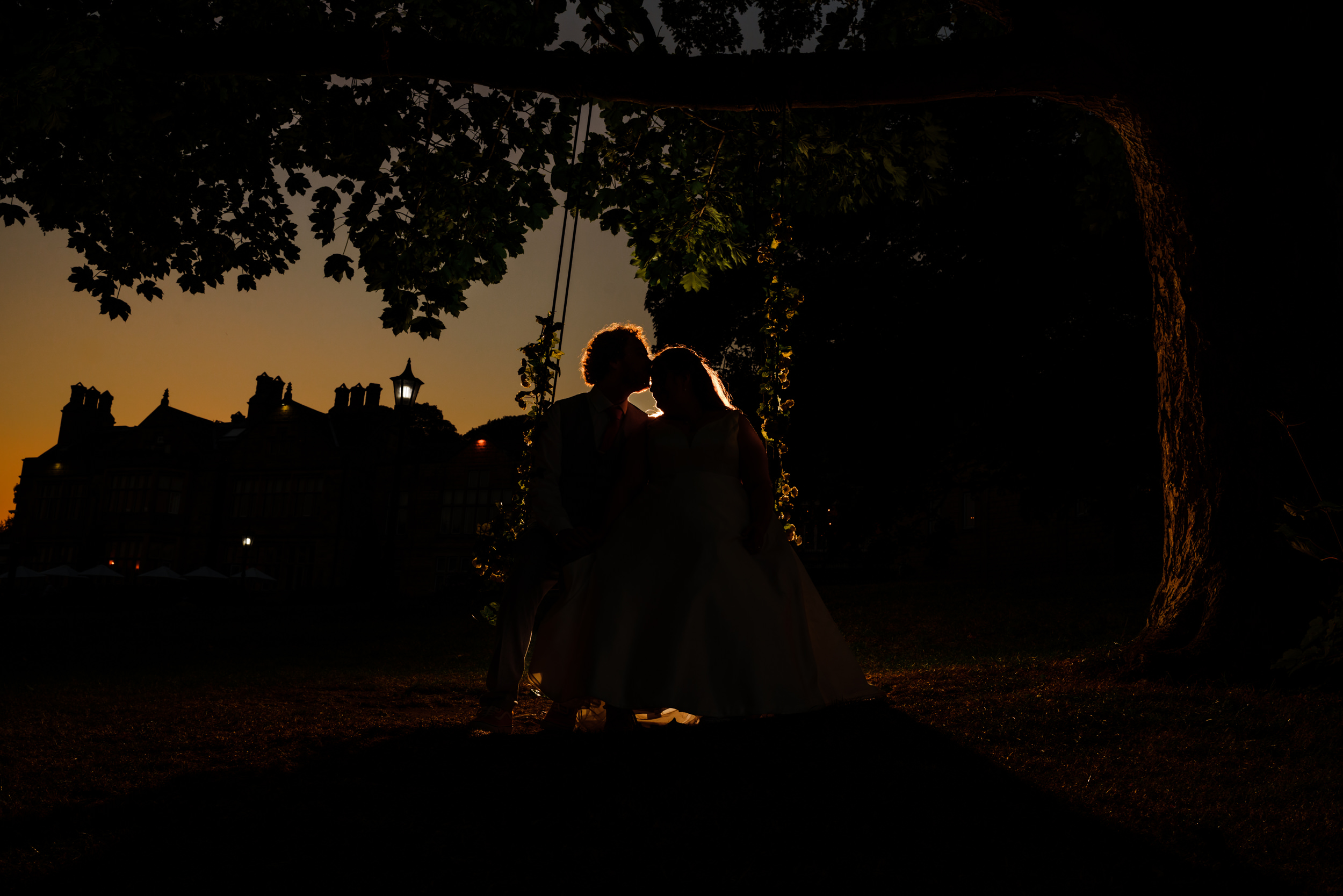 Backlit Evening portrait of the bride and groom at Hollins Hall Hotel on a swing