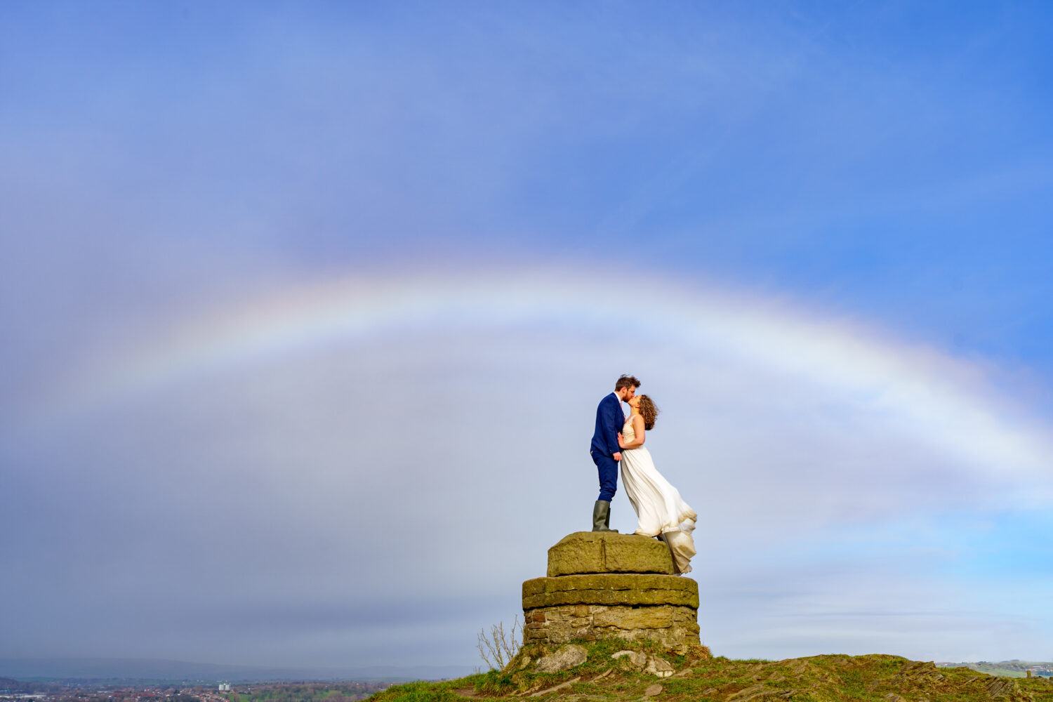 Couple kissing at Hartshead Pike in front of a rainbow