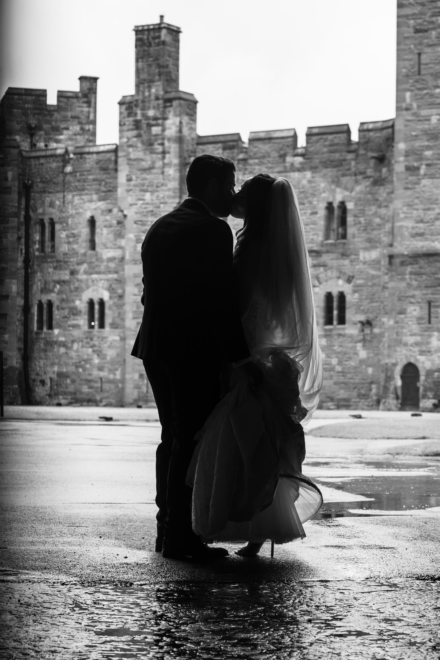 Bride and groom kissing in front of Peckforton Castle