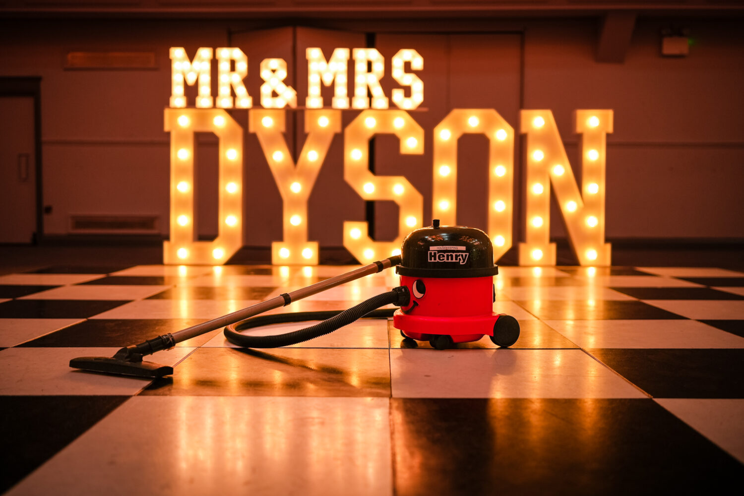 Henry the Hoover in front of a Mr and Mrs Dyson sign