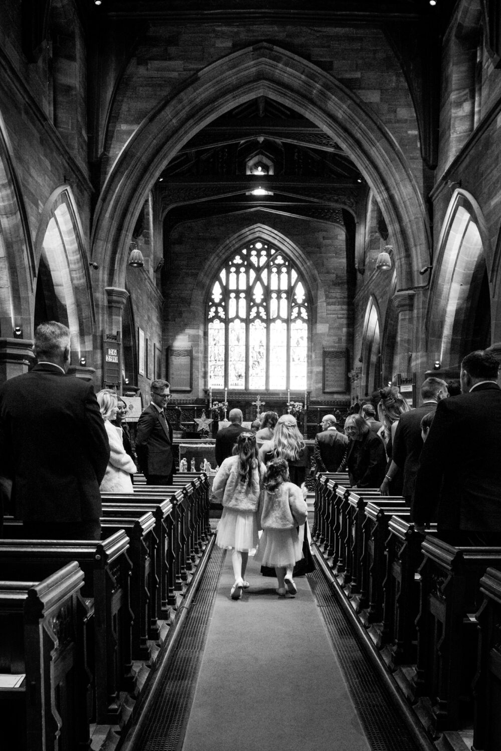 Flower girls following their mum down All Saints Church aisle