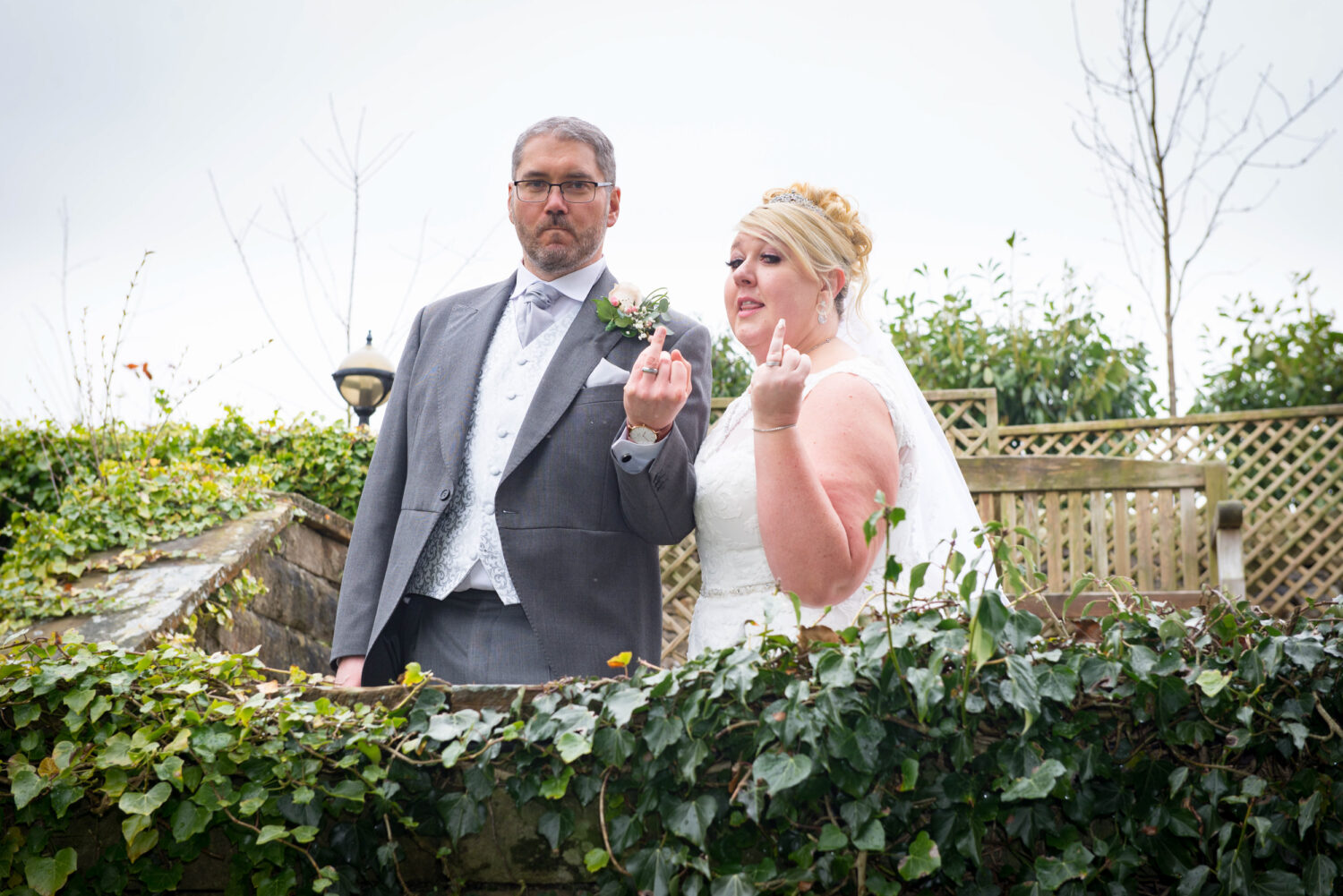 Bride and groom showing off their wedding rings outside Eaves Hall