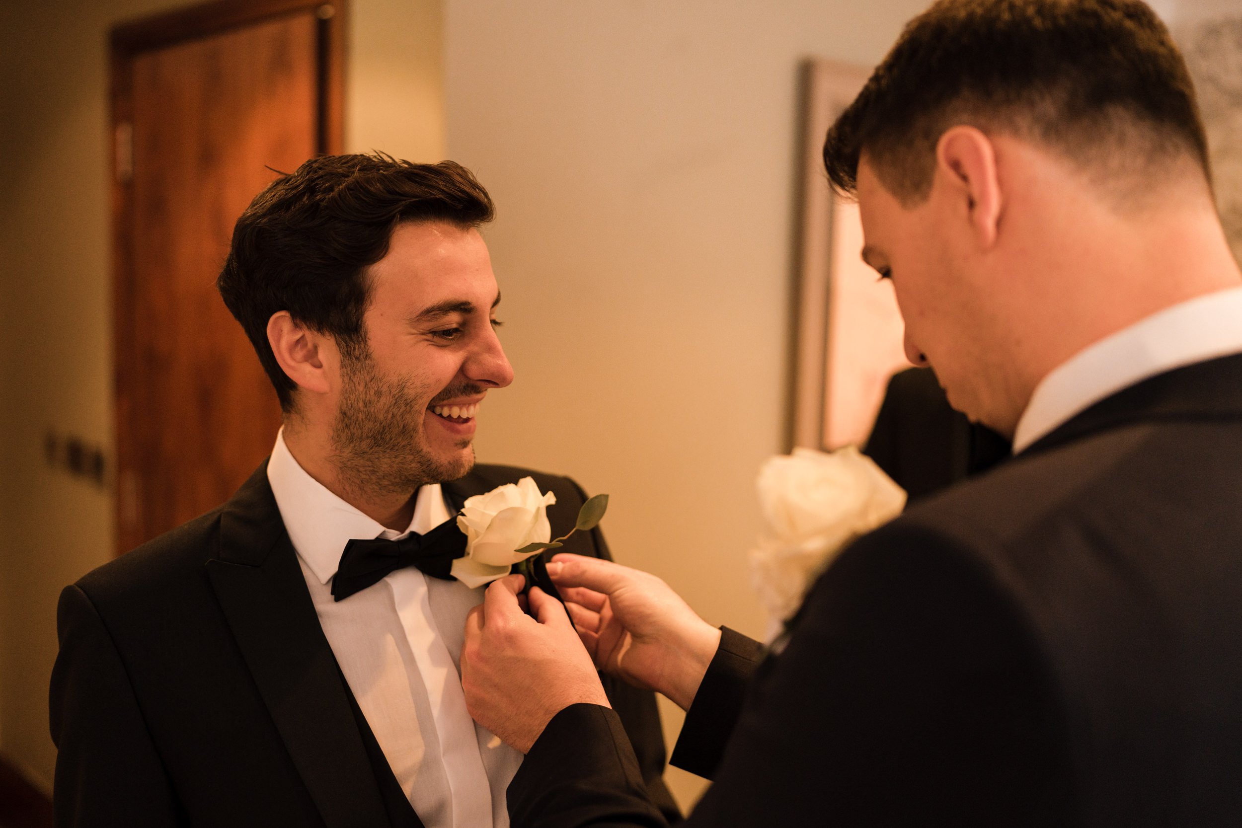 The groom fitting the best man's buttonhole at the Stanneylands