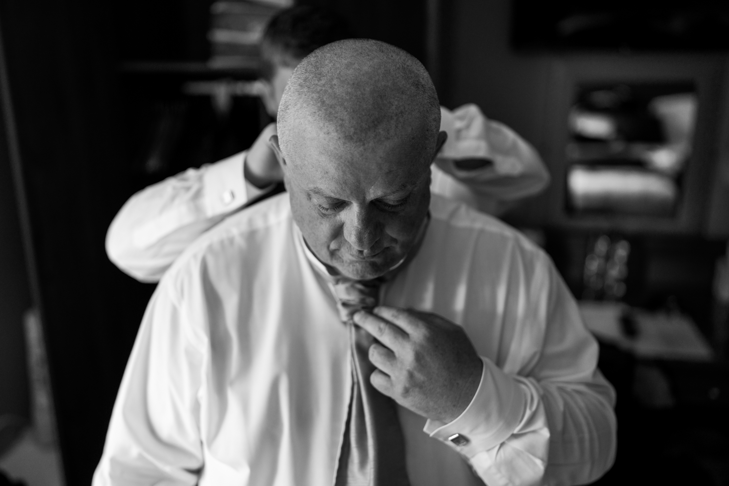 The groom's son fastening the groom's tie for him