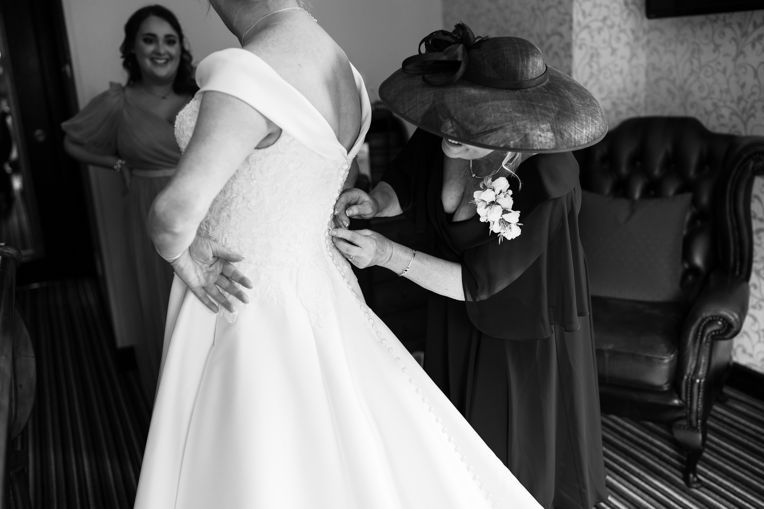 Bride's mother fastening her dress.