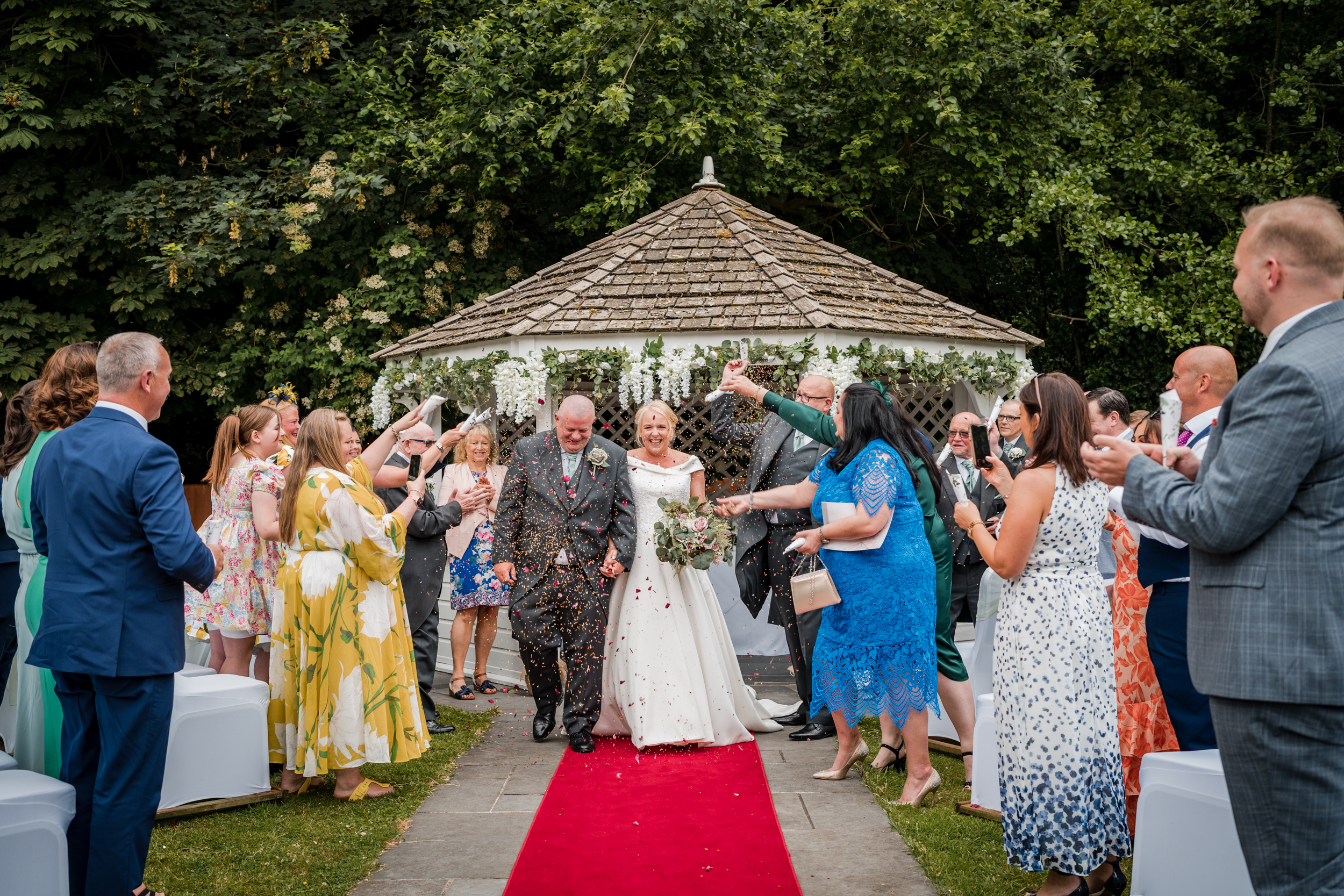 Bride and groom having confetti thrown over them after their Briars Hall Wedding ceremony