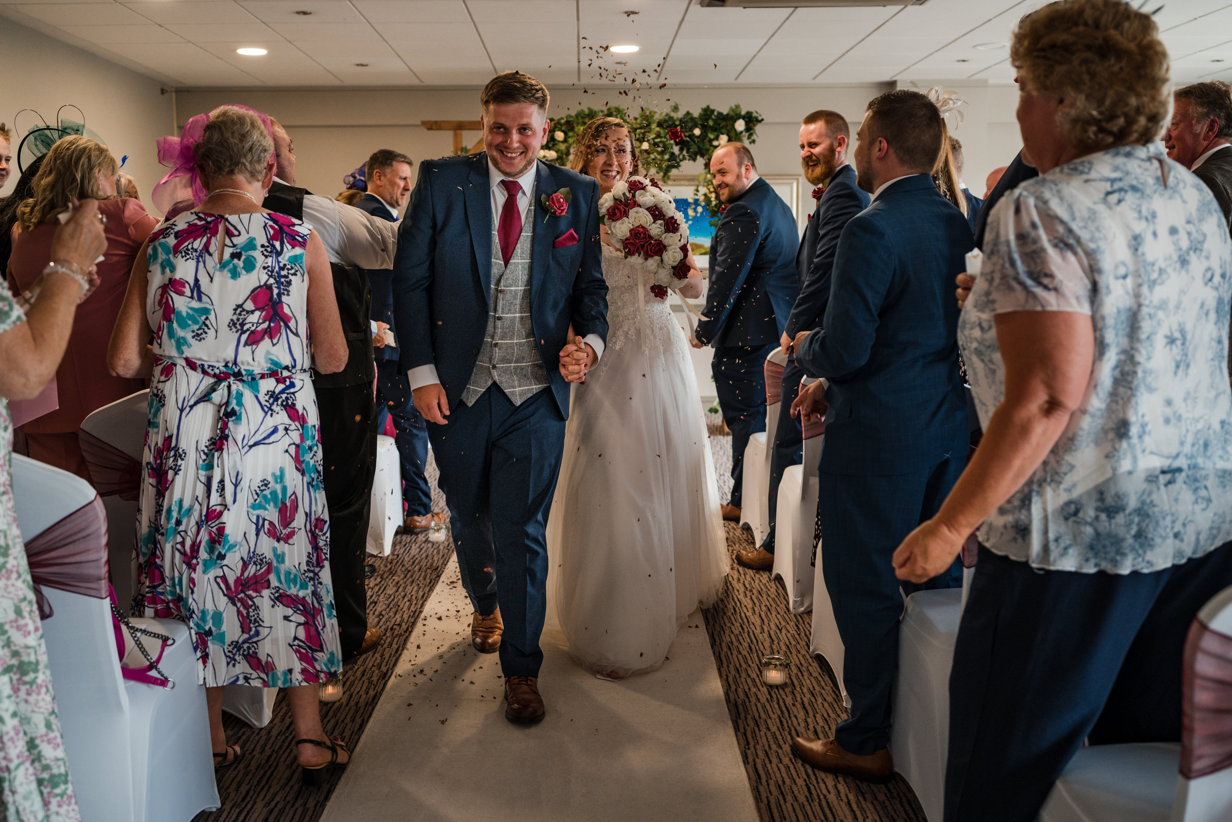Bride and groom walking down the aisle having confetti thrown over them at Cedar Court