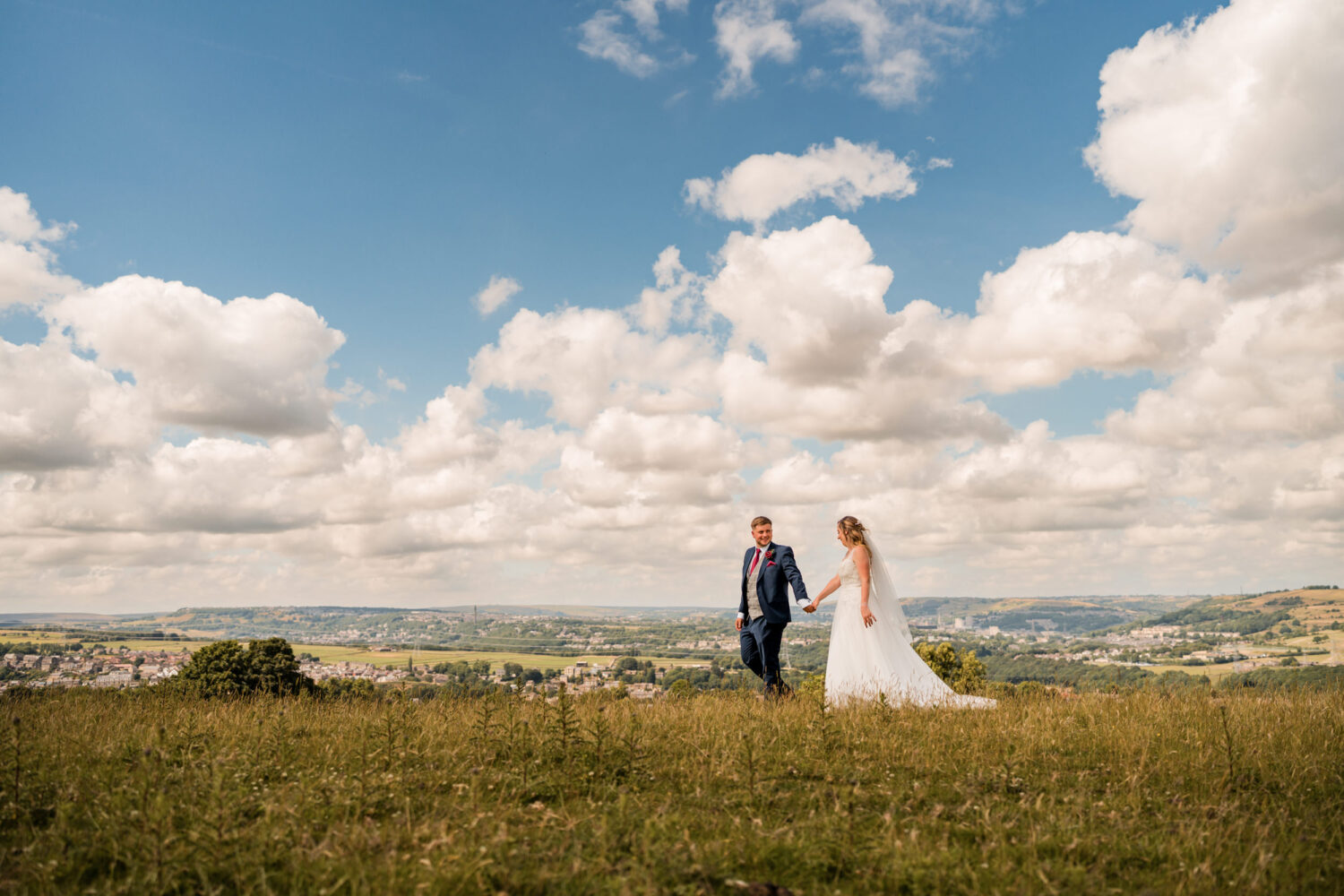 Bride and groom walking through a Lancashire field