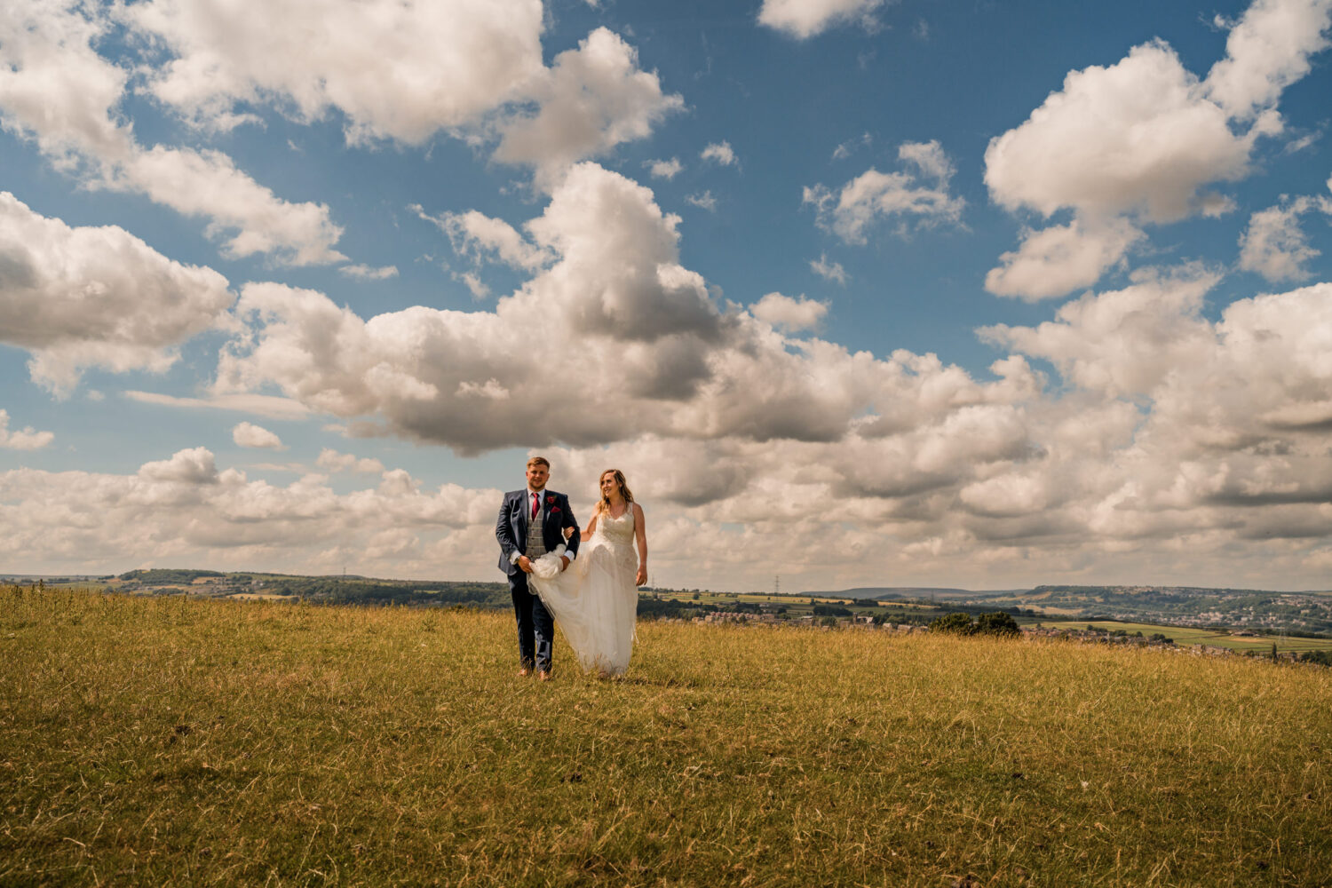 Bride and groom walking through a field near Cedar Court