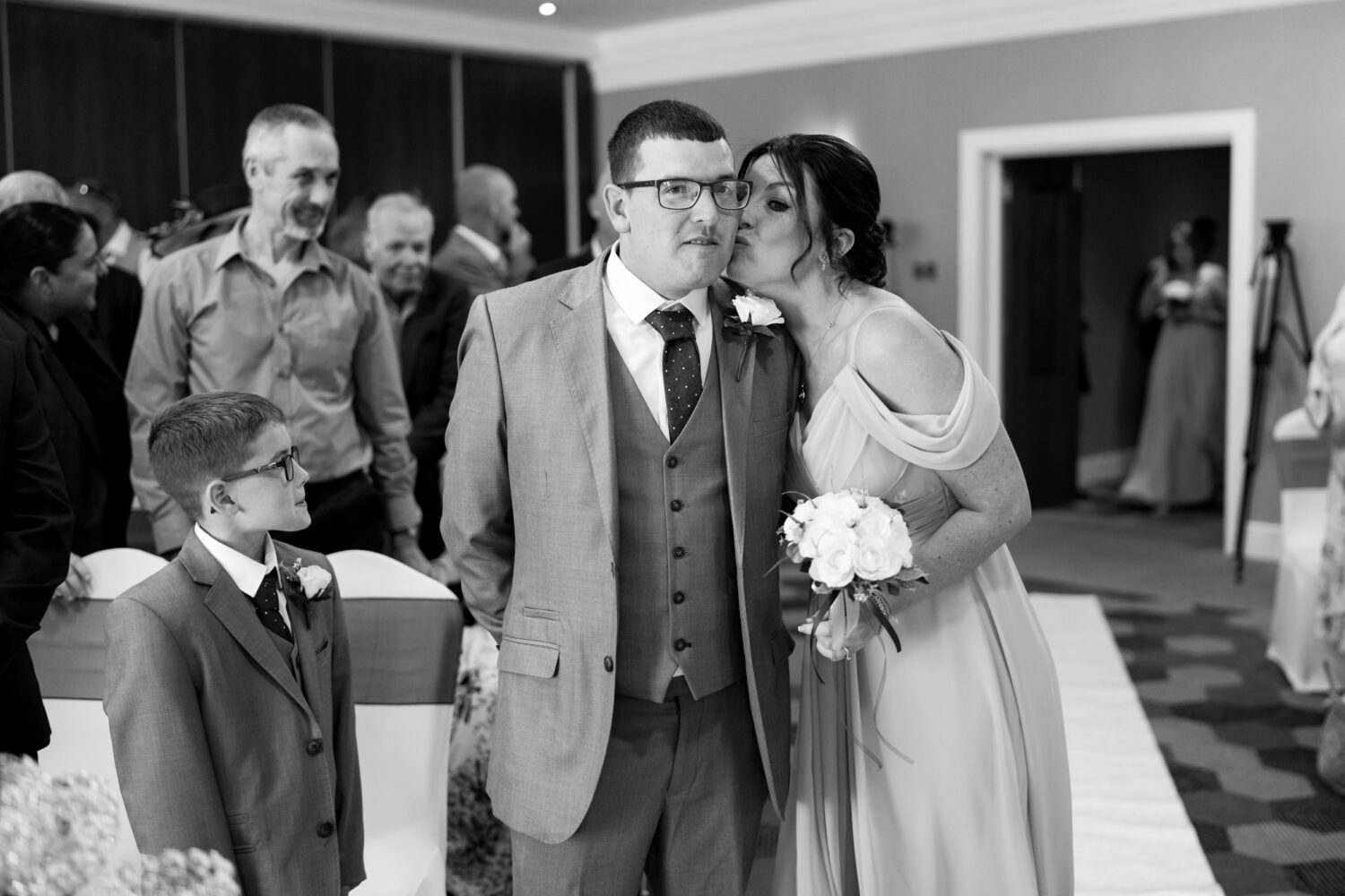 Bridesmaid kissing the groom on the cheek at Norton Grange