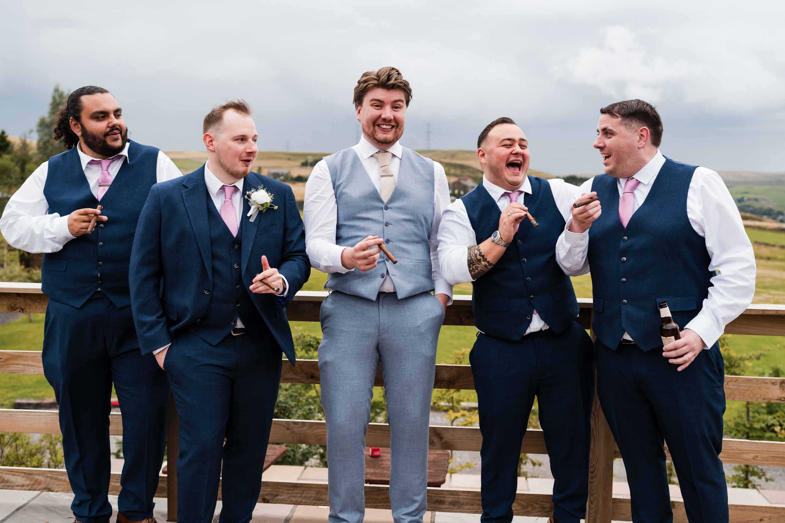 Groomsmen laughing and smoking cigars outside Grains Bar