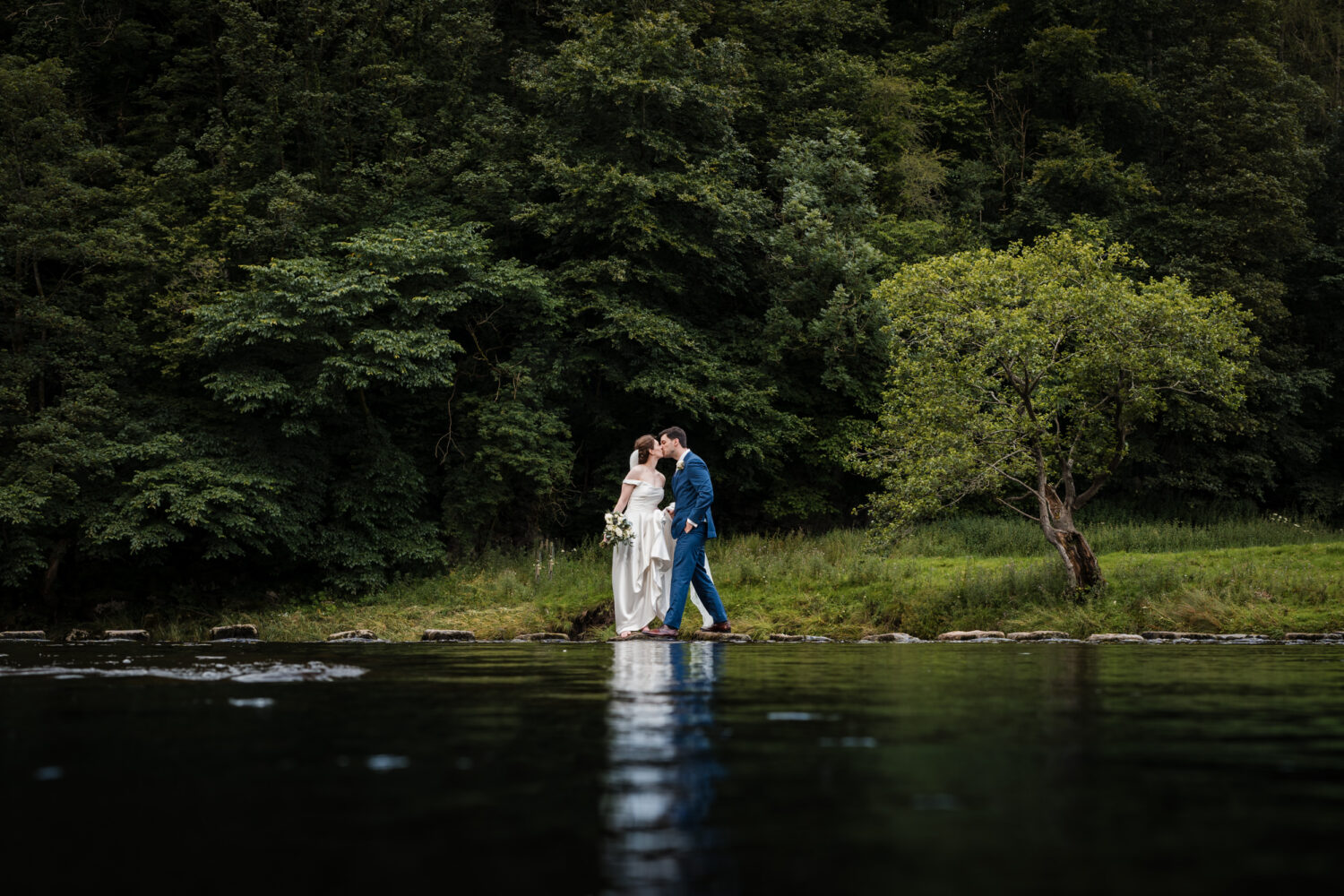 Bride and groom kissing on the Inn at Whitewell stepping stones in the Ribble Valley