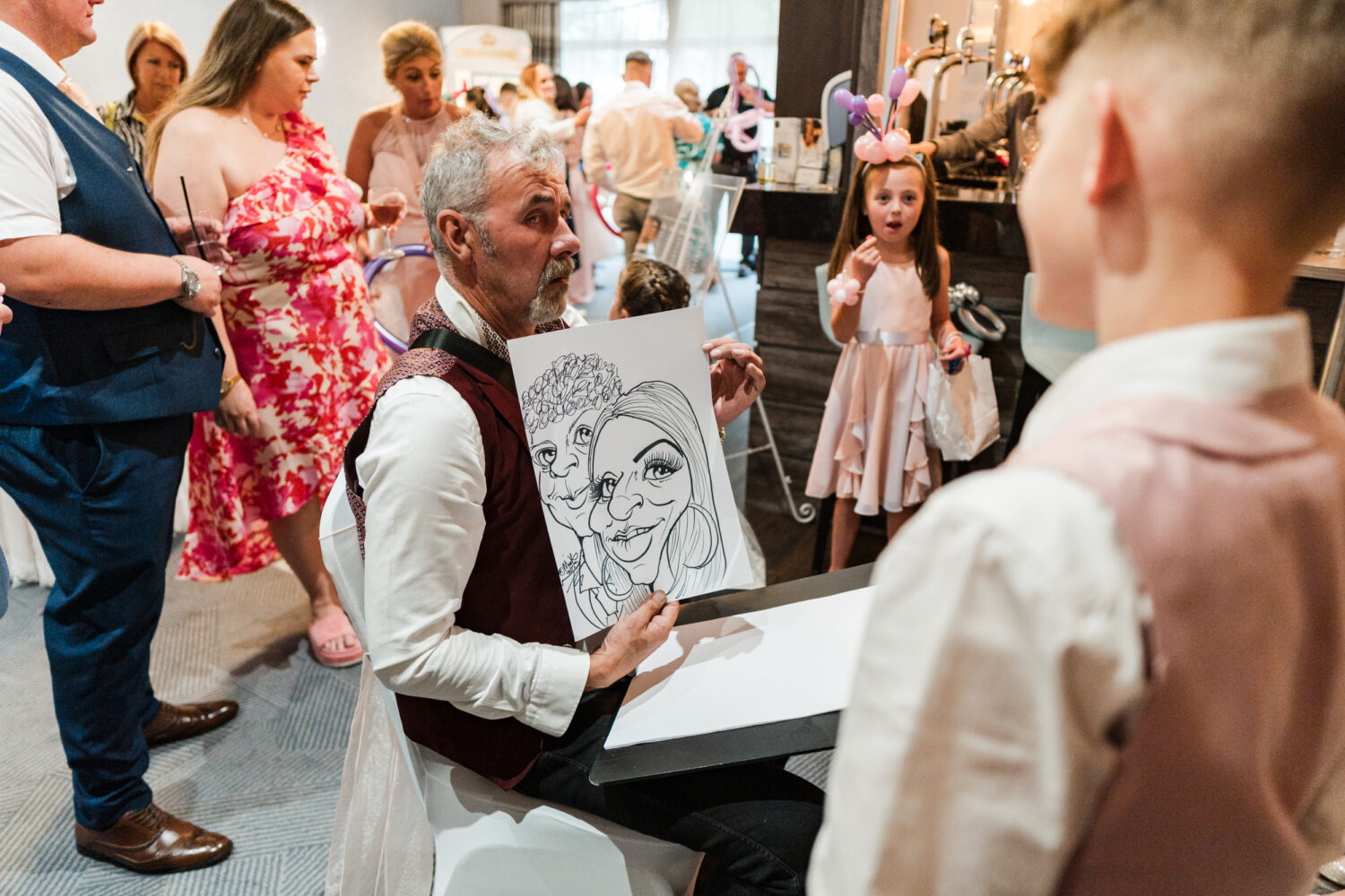 Caricaturist showing a young boy his portrait at Norton Grange.