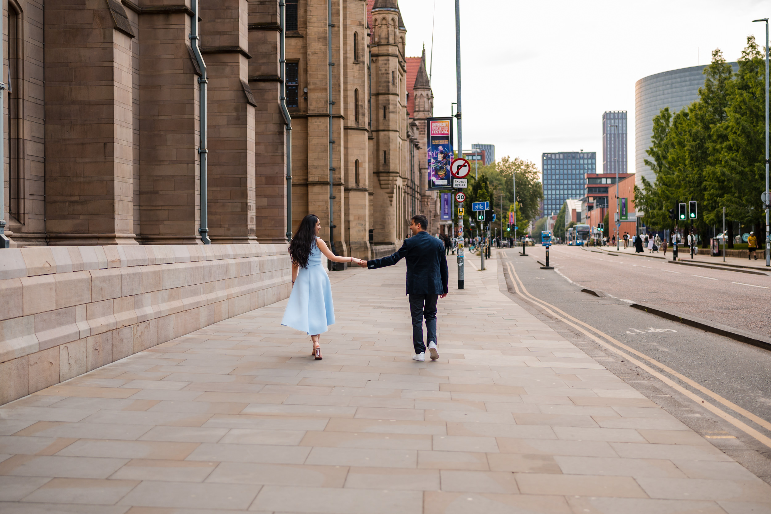 Couple walking along Oxford Road outside the University of Manchester.