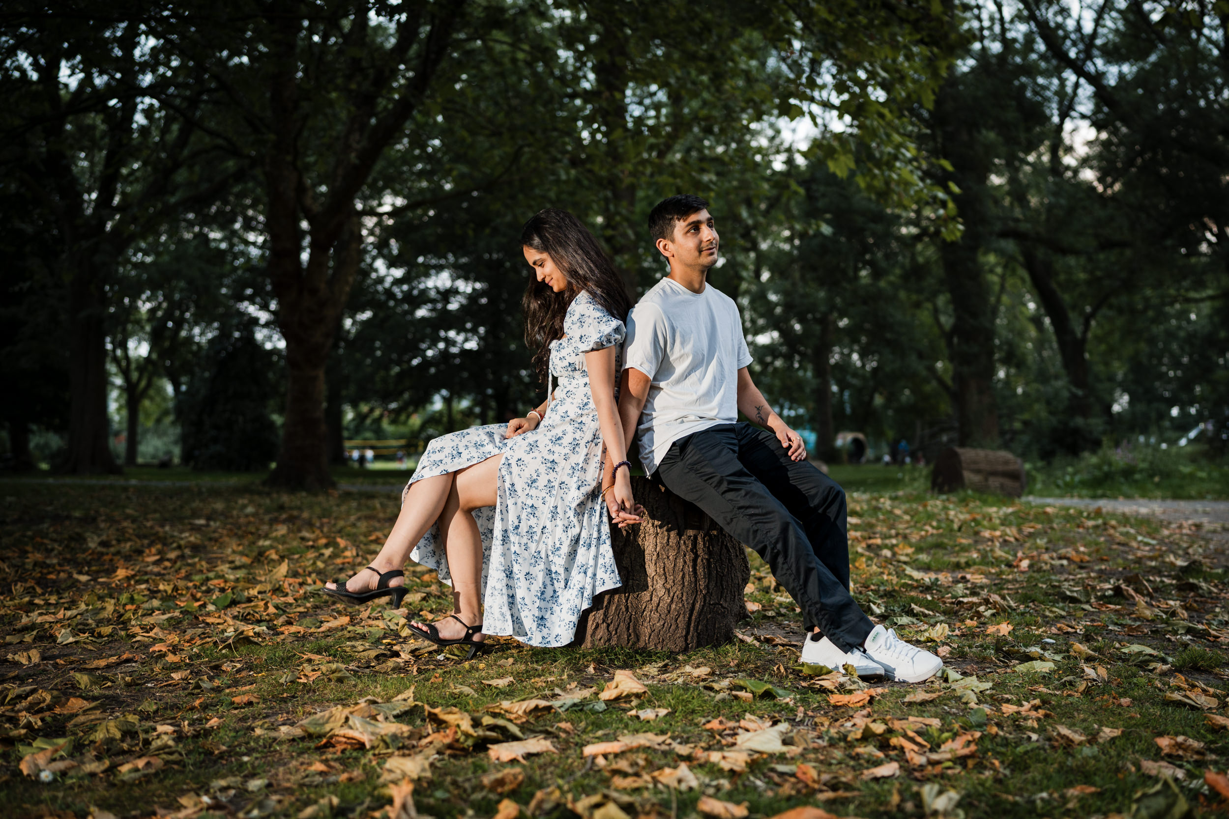 Engagement photo of couple sat on a log in Whitworth Park, Manchester.
