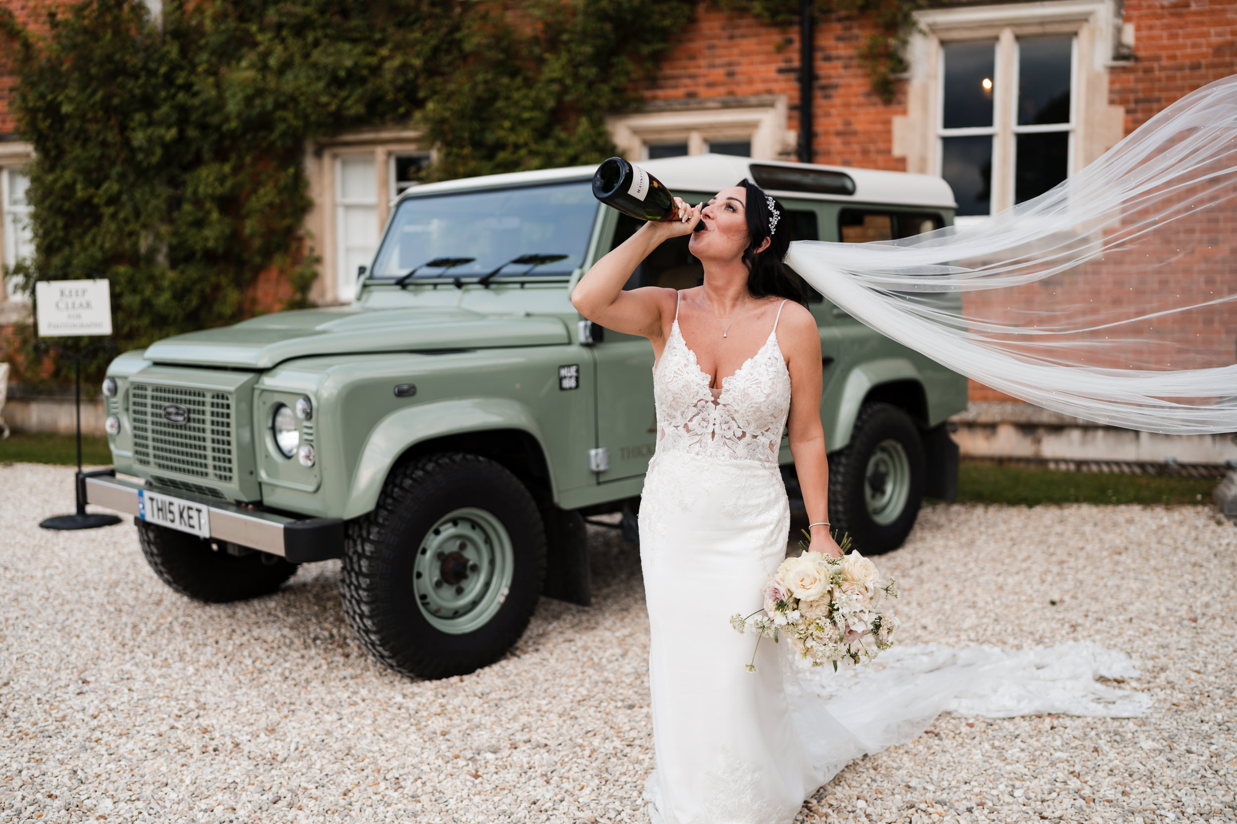 Bride drinking champagne from the bottle outside Thicket Priory