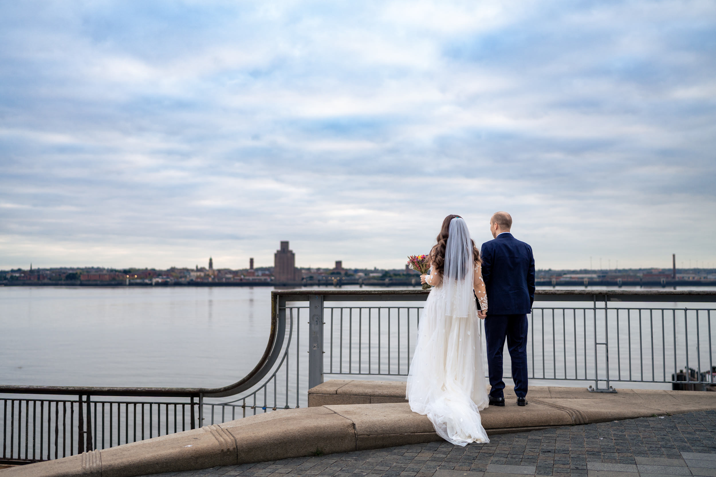 Bride and groom looking out over the river Mersey